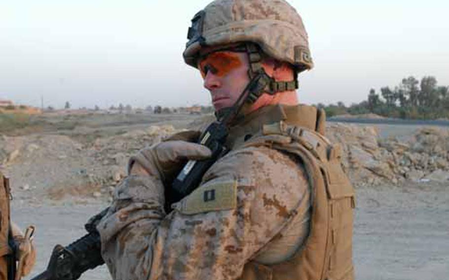 Capt. Seth MacCutcheon, L Company commander, 3rd Battalion, 7th Marine Regiment, radios to members of his unit for information while questioning possible witnesses about a shooting outside a mosque in South Hit, Iraq, on Friday.