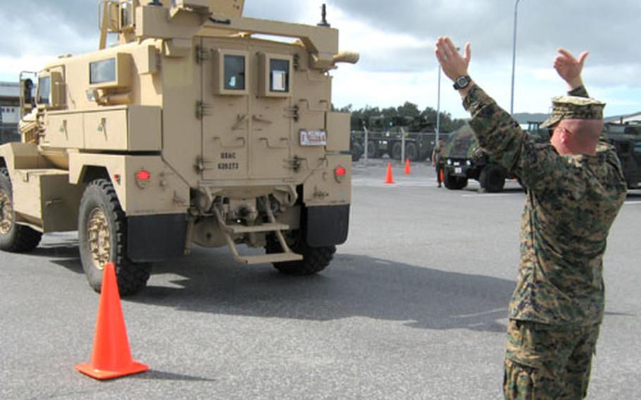 Sgt. Daniel J. Fisher, 25, of Milwaukee, the primary instructor for the MRAP course, acts as a ground guidefor a student backing up at Camp Hansen on Thursday.