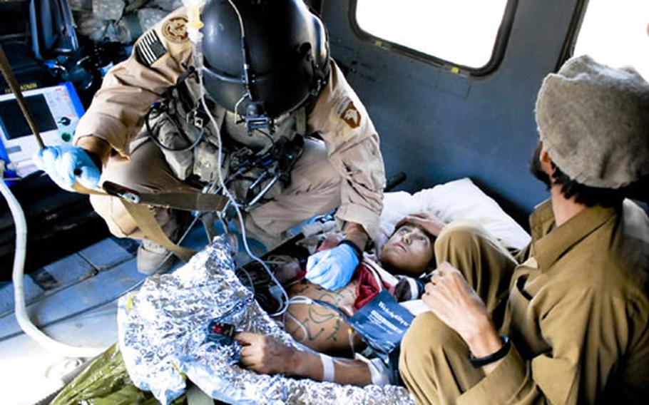 Staff Sgt. Matthew Kinney, a flight medic, writes vital statistics on the chest of an Afghan teen-ager injured by shrapnel during an insurgent attack on a U.S. outpost.