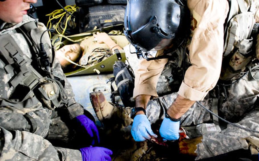 Staff Sgt. Matthew Kinney, a flight medic, treats a wounded U.S. soldier while Staff Sgt. James Frailey, a helicopter crew chief, looks on. The soldier was wounded after his patrol came under fire from insurgents and was apparently hit by an errant U.S. mortar round, the military said. One U.S. soldier was killed. An Afghan soldier, in the rear, was wounded.