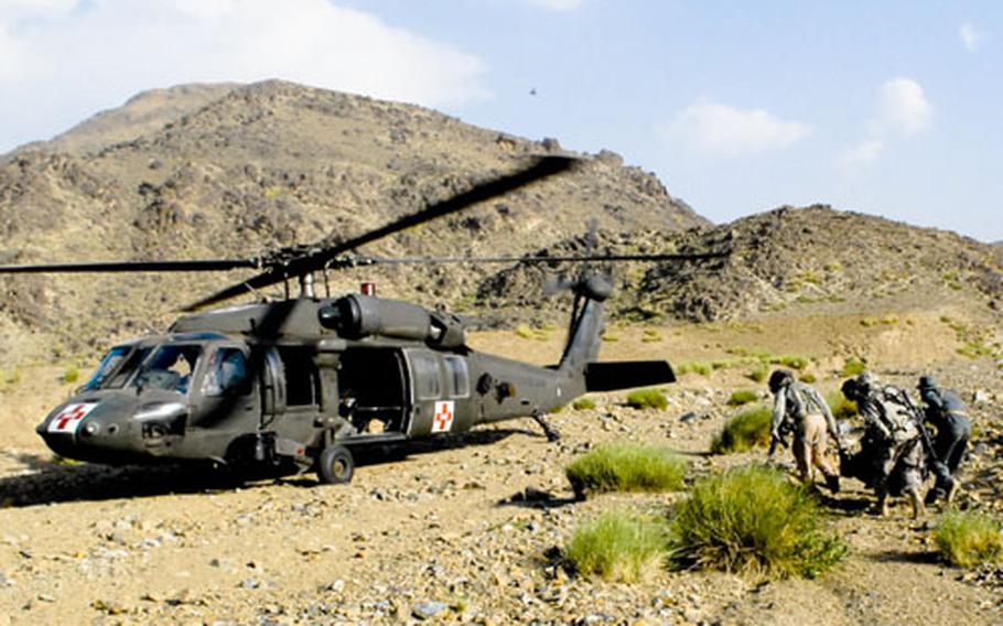 U.S. troops and an Afghan policeman carry the body of a U.S. soldier killed in a roadside bombing to a waiting helicopter.