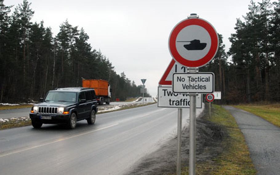 A truck in the background travels on the tank trail which runs parallel to an ordinary on-post road in the foreground in Grafenwöhr, Germany. The tank trail connects the communities of Vilseck and Grafenwöhr, and some soldiers would like to be able to drive private automobiles on the trail to save travel times between the two bases.