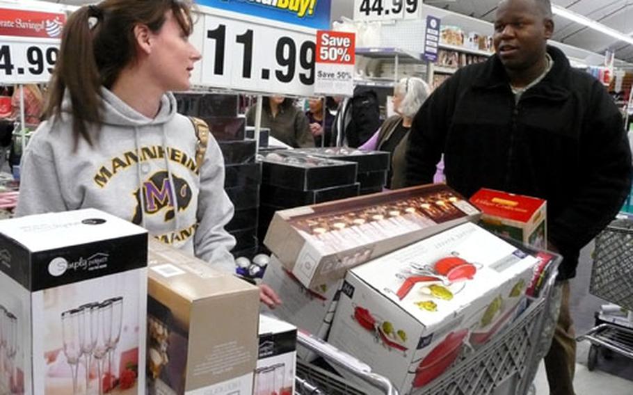 Sgt. Felix Eady, a member of the 44th Signal Battalion, and his wife, Dacia, wait on line at the Army and Air Force Exchange Service main store in Mannheim with two shopping carts full mostly of dishes and glassware.