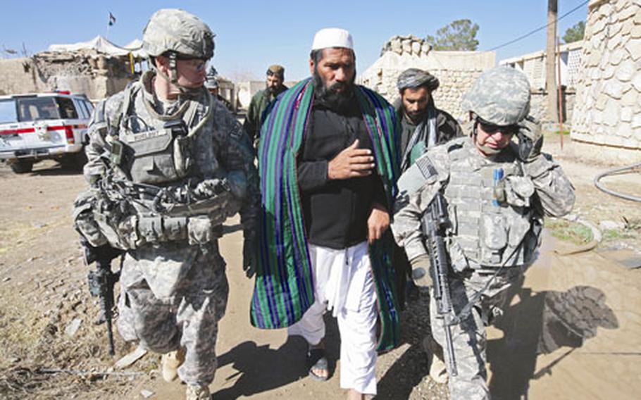 Lt. Col. Dan Hurlbut, left, and Haji Noor Mohammad Akhund, district leader of Maiwand district, walk from the district government center to inspect a voter registration site in Kandahar province, Afghanistan.