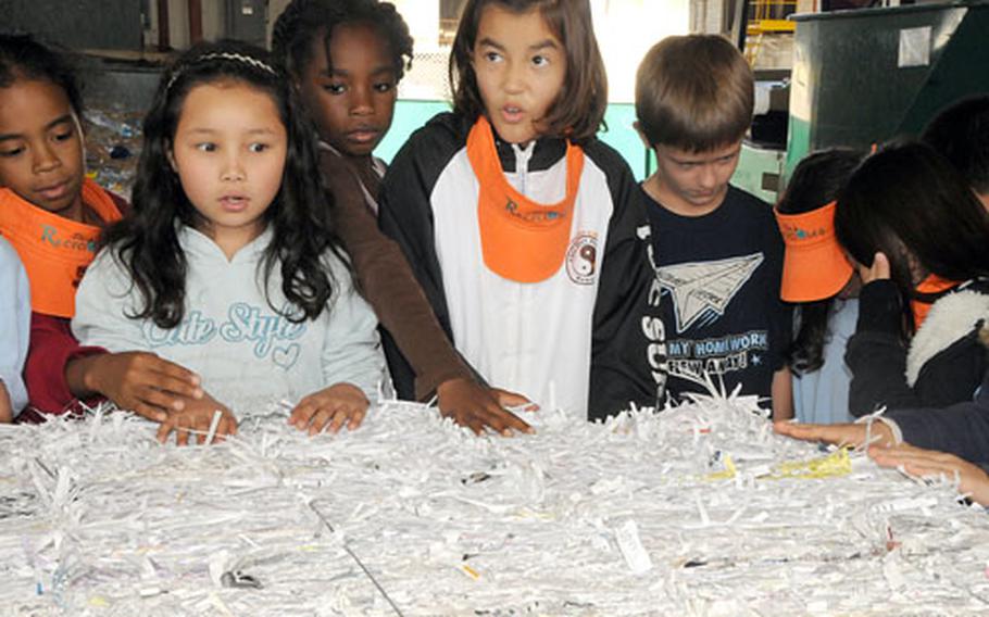 Third-graders from Kinser Elementary School, on Camp Kinser, Okinawa, listen in amazement as a worker at Friday at the Camp Foster Recycling Center tells them this block of shredded paper weighed 1,000 pounds.