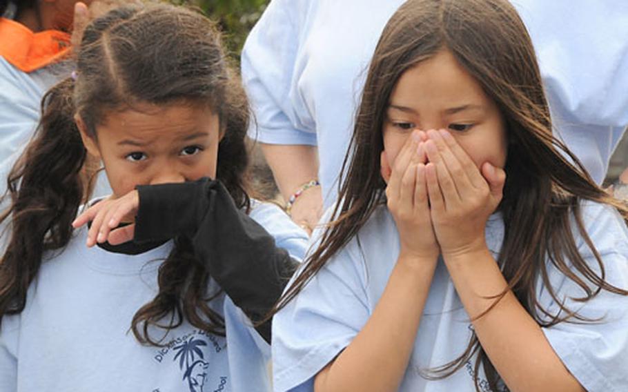 Analyn Brito, left, and Akina Johnson, third-graders at Kinser Elementary School, cover their noses at the smell of the trash at Kurashiki Kankyo, a landfill in Okinawa City. Two Kiser classes visited the landfill to learn aboout what happens to garbage once it&#39;s thrown away on Okinawa.