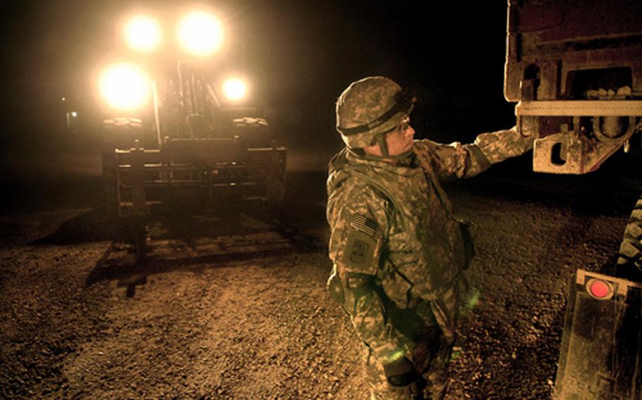 Pfc. Christopher Trumbull, a soldier assigned to the 172nd Support Battalion, secures a cargo container for transport during a late night convoy early Tuesday morning at Forward Operating Base Iskan. U.S. forces will turn the FOB over to the Iraqi Ministry of Electricity within the month. The 172nd Support Battalion is deployed from Schweinfurt, Germany.