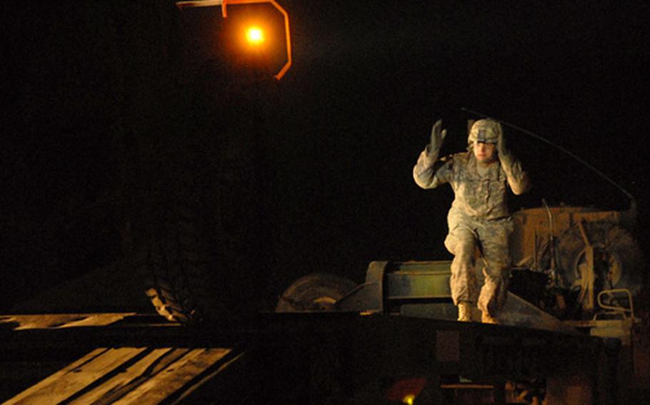 Pfc. Justin Ferrara, a soldier assigned to the 172nd Support Battalion, marshals a humvee onto a flatbed trailer for transport during a late night convoy late Monday at Forward Operating Base Iskan.