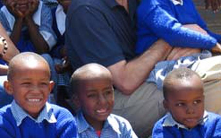 Navy Lt. David Masterson, command chaplain at Camp Fuji, Japan, sits with children at the Kinyago-Dandora School in a slum area of Nairobi, Kenya. Masterson spent January teaching at the school and helping children suffering from PTSD.