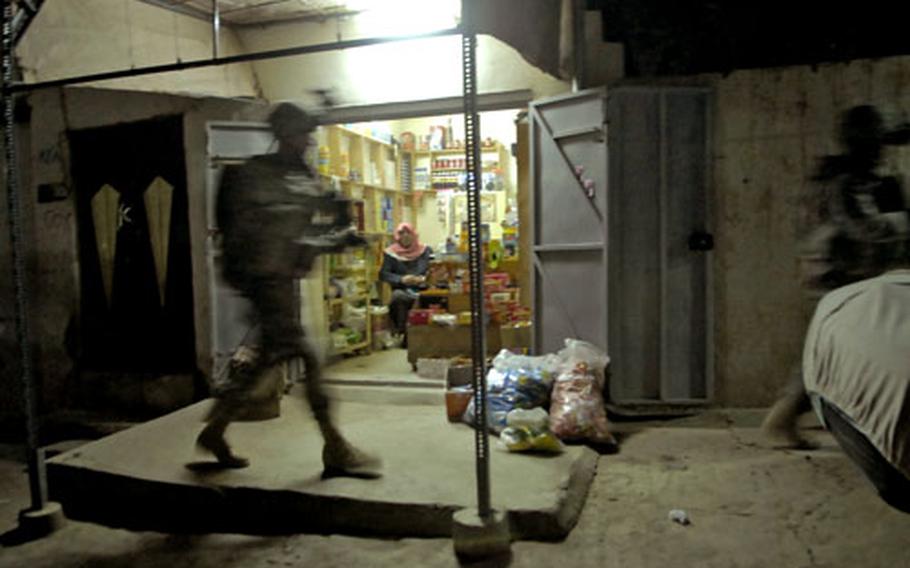 A U.S. soldier passes a shop during a night patrol in Mosul.