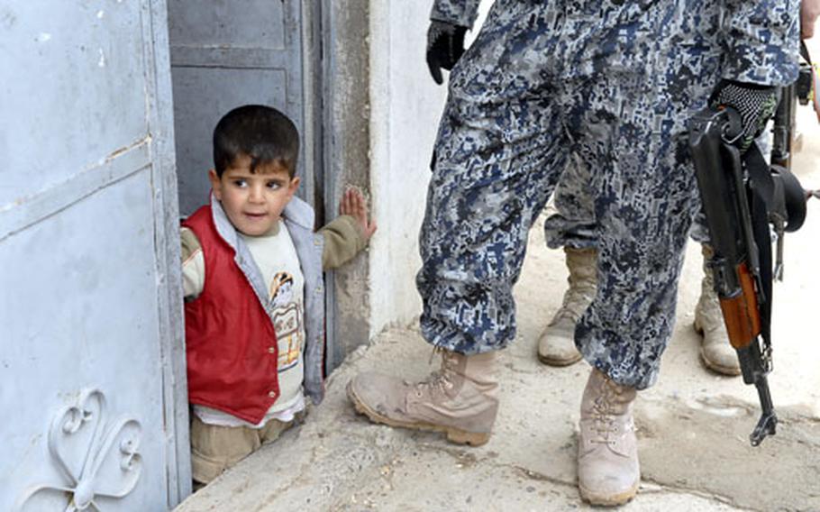 An Iraqi child peeks out at a joint patrol of Iraqi National Police and U.S. soldiers in Mosul.