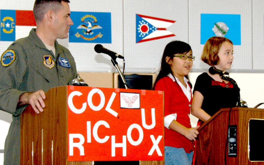 Air Force Col. Lenny Richoux, left, vice commander of the 18th Wing at Kadena Air Base, Okinawa, is introduced to two student helpers, Katrina Stebbins, a fourth-grader, center, and third-grader Rachael Foley, during a round of “Are you smarter than a Firebird?”