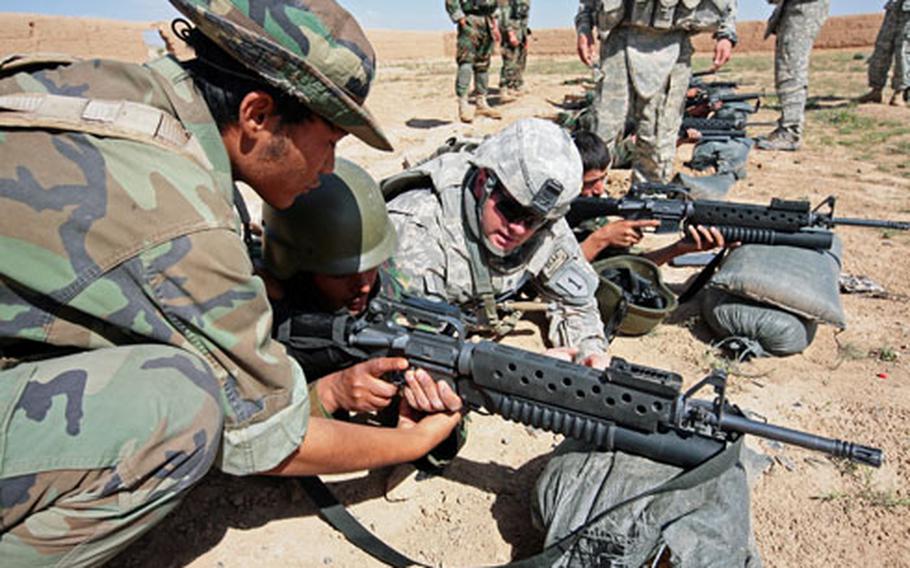 Spc. Michael Alfassa, 25, corrects an Afghan soldier’s grip during the training in Maiwand district, Kandahar province, Afghanistan. The U.S. soldiers are from Company D, 2nd Battalion, 2nd Infantry Regiment and are helping the Afghan army make the transition from Soviet-era weaponry to the rifles used by the U.S. Army.