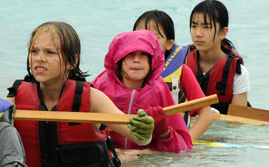 Taryn Sobey, left, 10, a fifth-grader from Camp Foster’s Zukeran Elementary School, and other children paddle the bamboo raft they built at Yoron Island, Japan, on Tuesday. “It was fun and hard and cold,” Taryn said. Below: Joshua Thomas, left, 11, and Jerry Dubois, 11, build sand forts.
