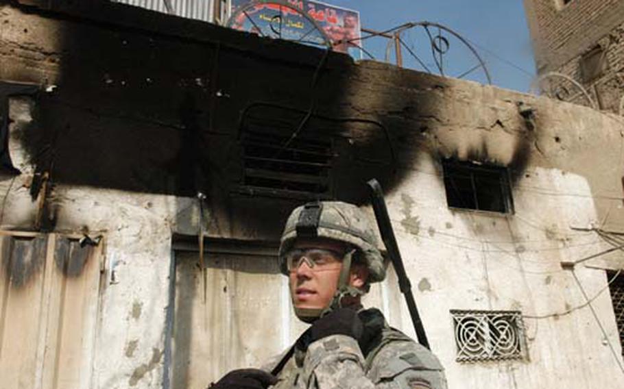 First Lt. Mike Russo of 2nd Platoon, Alpha Troop, 5th Squadron, 37th U.S. Cavalry Regiment stands outside a burned-out building destroyed during an eight-hour firefight on March 28. U.S. and Iraqi forces battled the local followers of a "Sons of Iraq" leader who had just been arrested. Last week, Russo and his men visited the shop’s owner to arrange compensation.