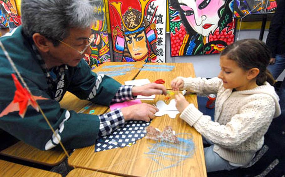 A member of the Japan Kite Association helps Sloane Youtsey, 7, make her own kite.