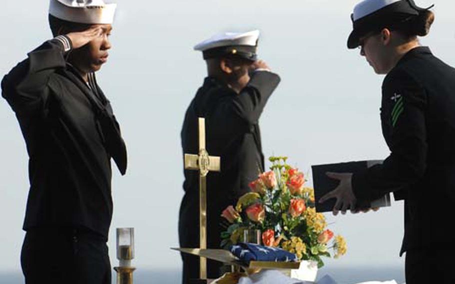 Petty Officer 3rd Class Fred Banks salutes as Seaman Tiffany Roach prepares to present cremated remains to Capt. Brent Canady during a burial at sea aboard the USS Essex on Sunday. The Essex and the USS John C. Stennis both held burial ceremonies over the weekend.