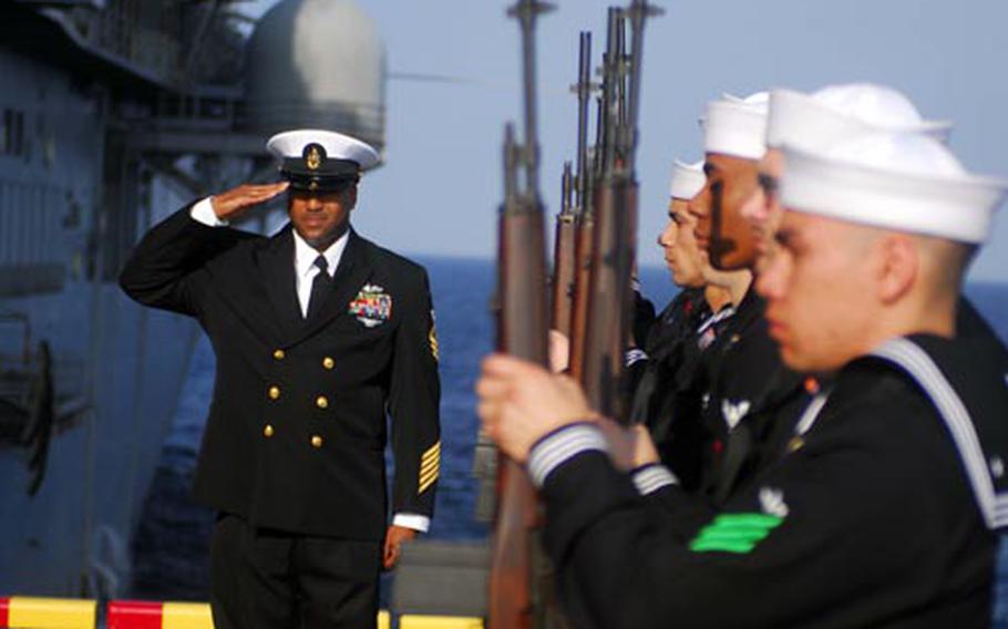 A firing squad presents arms during a burial at sea for retired Navy sailor Paul H. Stephens aboard forward deployed amphibious assault ship USS Essex on Sunday.