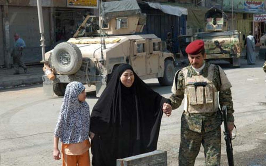 A local woman gets helped to a free clinic April 1 hosted by the U.S. and Iraqi militaries in the east Baghdad Fadhil neighborhood. Officials with the 82nd Airborne Division’s 3rd Brigade said the event was an effort to win public support after the March 28 arrest of a local militia leader.