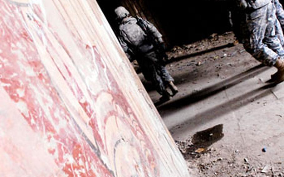 U.S. troops pass a shattered mural inside the ruins of the center.