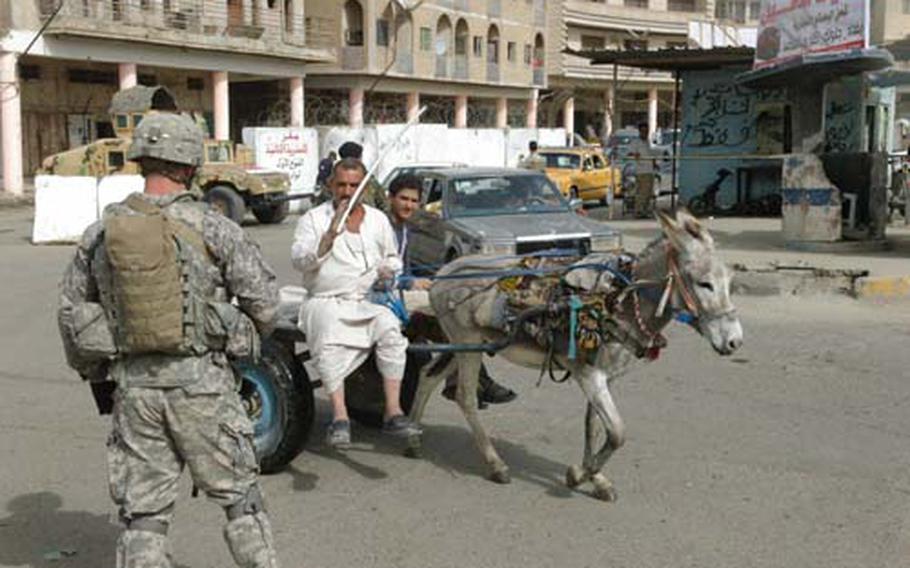 A paratrooper with Alpha Troop, 5th Squadron, 73rd U.S. Cavalry Regiment signals a local man and his donkey through an intersection in the Fadhil neighborhood of east Baghdad. U.S. forces here are working to build up a nascent Iraqi army and government presence after the arrest of a local militia leader last month who essentially ran the area.