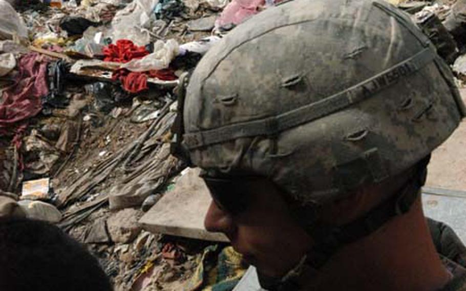 A paratrooper with Alpha Troop, 5th Squadron, 73rd U.S. Cavalry Regiment stands next to a massive trash pile in the Fadhil neighborhood of east Baghdad last week.