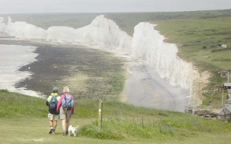 A couple of walkers stroll past the white cliffs of Dover.