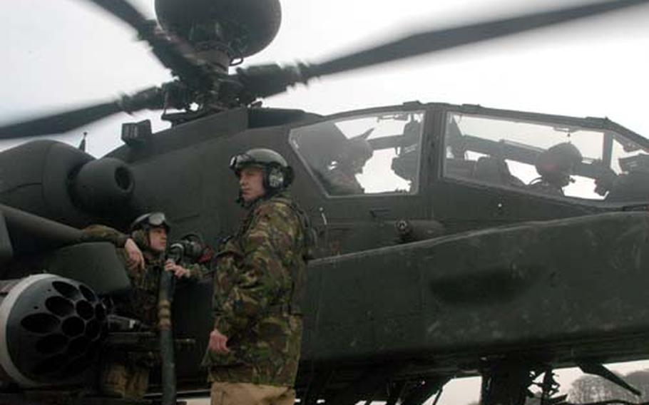 British maintainers gas up a British Apache helicopter at Salisbury Training Ground, near Stonehenge.