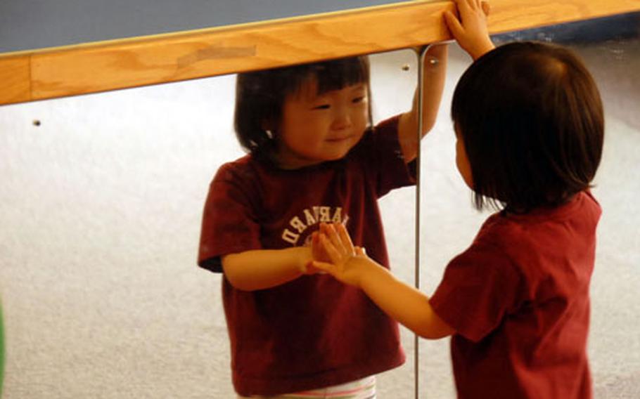 Lindsay Choe, 2, smiles at her reflection in a mirror at the Child Development Center at U.S. Army Garrison-Yongsan. The garrison commander was to sign a covenant on Saturday offering new benefits to CDC employees.