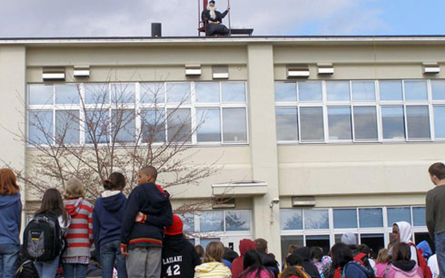 Cummings Elementary School principal Scott Sterry reads to students from atop the school’s roof, dressed as Professor Dumbledore from the Harry Potter series at Misawa Air Base, Japan, on Thursday. Sterry promised he would read from the roof in costume if students read 6,000 books in two months. The students finished off 6,026 books.