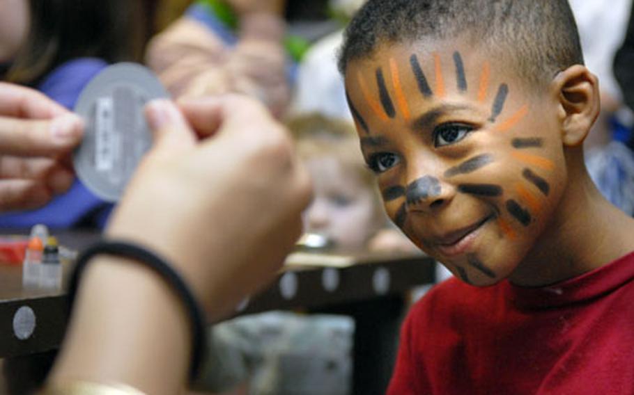 Xavier Woodard, 7, checks out the handiwork of Michelle Zapata, a face painter and senior at Baumholder High School, Friday during the Buc Night fundraiser in Baumholder.