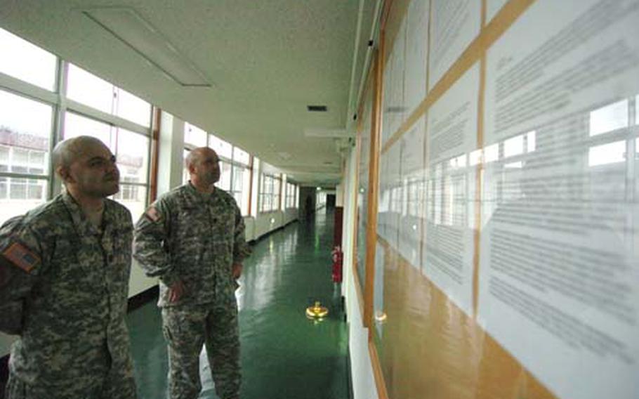 I Corps (Forward) Headquarters Detachment Commander Capt. Robert Diaz, left, and First Sgt. Joseph Anastasio, observe their growing bulletin board filled with command policies and announcements at Camp Zama on Tuesday.