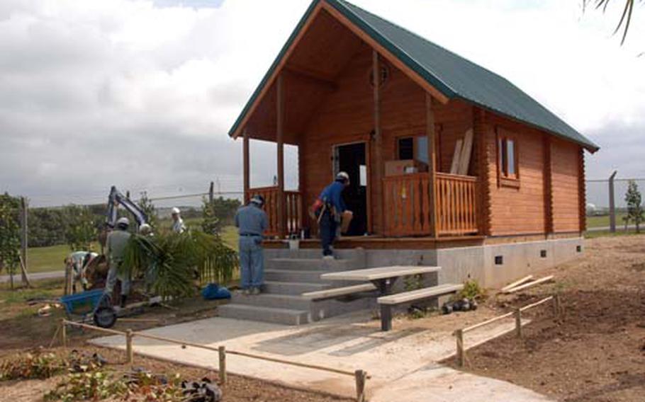 Workers install palm trees and work on the exterior and interior of a beach cabin at Torii Station. The cabin is one of four newly built cabins on the beachfront facility.