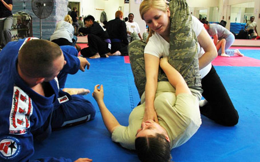Under the guidance of one of their instructors, two students practice performing a triangle choke, a jujitsu move, during a sexual assault prevention self-defense class Thursday at Yokota Air Base, Japan.