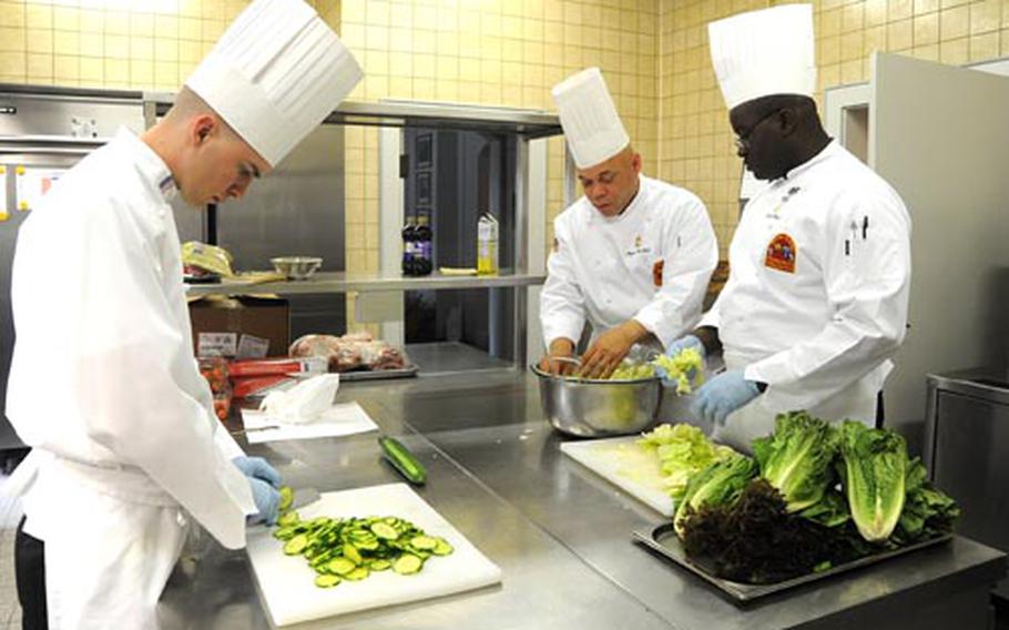 Spc. Andrew Nicholson, left, chops cucumbers while Master Sgt. Major Luckett, center, and Spc. Quincy Queen prepare a salad in the Keyes Building kitchen on Campbell Barracks in Heidelberg, Germany.
