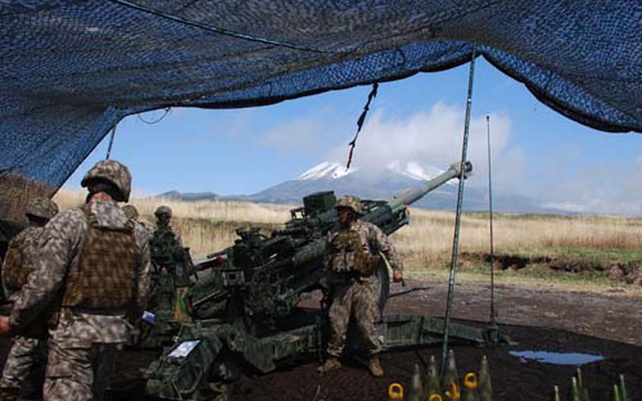 Marines fire a 155 mm round from a M777 howitzer, temporarily hiding Mount Fuji from view, while training at Camp Fuji.