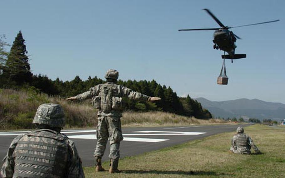 Soldiers get ready as a UH-60 Blackhawk helicopter carrying supplies prepares to land during 35th Combat Sustainment and Support Battalion&#39;s sling-load training at Camp Fuji.