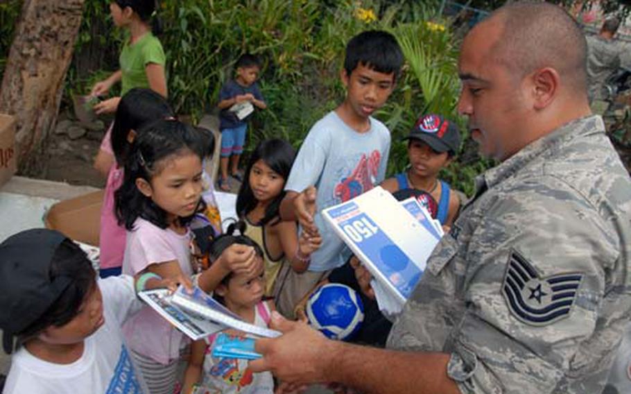 Tech. Sgt. Luis Angel Aviles, of the 56th Fighter Wing at Luke Air Force Base, Ariz., hands out paper and other school supplies to orphans at the Duyan Ni Maria Children’s Home in Angeles City, Philippines, on Friday.
