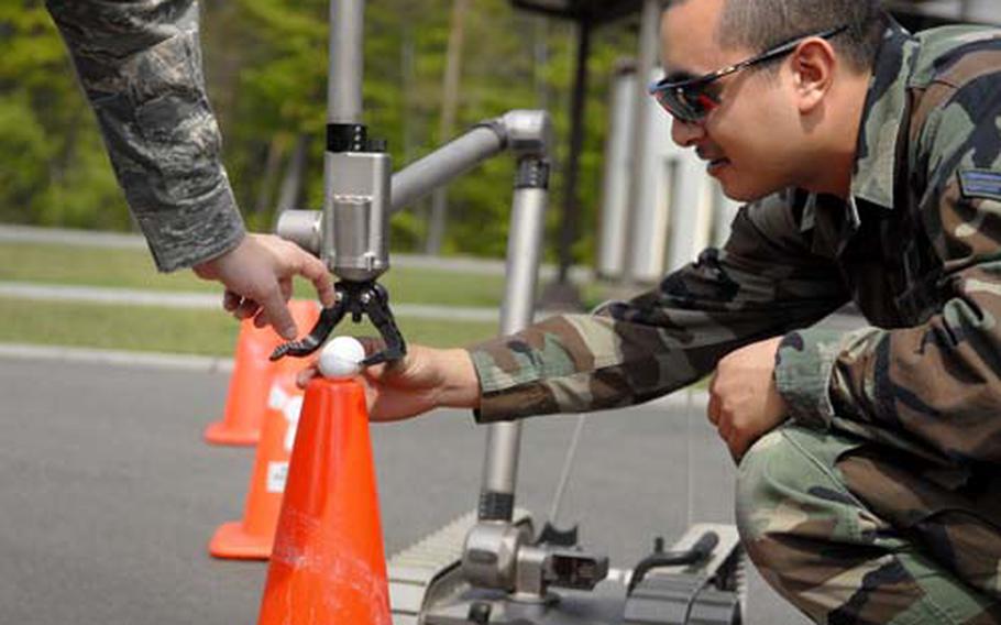 Airman 1st Class Guadalupe Corona, a bomb disposal apprentice with the 835th Civil Engineering Squadron, examines a slightly cracked egg that he moved from cone to cone with a robot on Tuesday during training at Ramstein Air Base. Corona will be expected to go from handling eggs to disarming bombs.