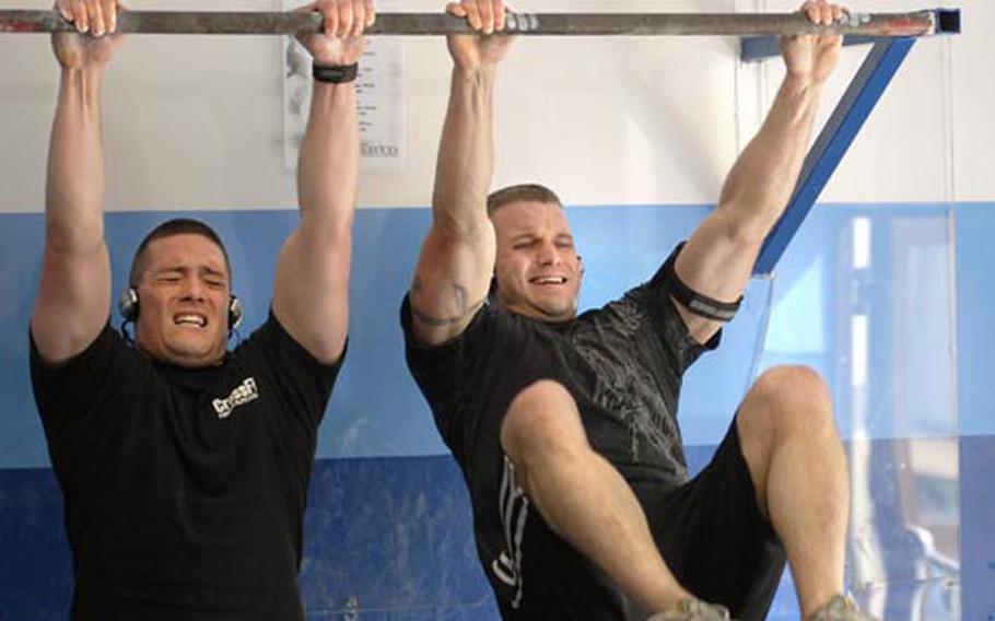 Tech. Sgt. Brian Bowen, right, pulls through 50 "Knees to Elbows" with Capt. Jeremiah Buckenberger during an afternoon workout Friday at Ramstein Air Base&#39;s North side gym. Bowen is taking his CrossFit workout skills to the CrossFit world games this July in California after finishing second earlier this month at the European games in Ireland. Bowen works in the air procedures flight at U.S. Air Forces Europe headquarters.