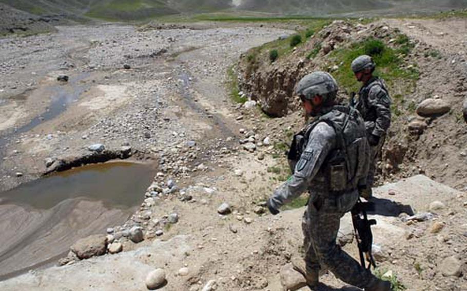 Spc. Chris Turner and Cpl. Derick Jenkins, members of a Task Force Warrior personal security detachment, check beneath a bridge for roadside bombs April 23 in Kapisa province. The task force’s area is most dangerous in this eastern province.