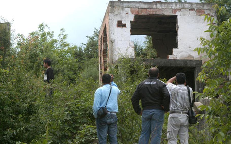 Ethnic Roma refugees who used to live in the village of Perlepnica on the outskirts of Gnjilane, Kosovo, survey one of the ruined homes they hope to return to. Ten years after NATO forces entered Kosovo, ethnic divides are still clearly evident.