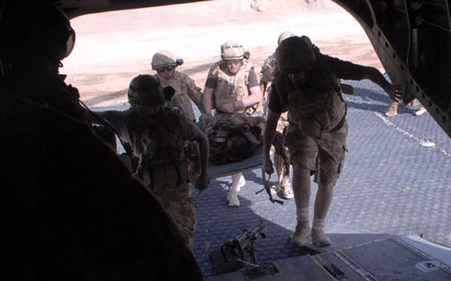 Members of the British military&#39;s Medical Emergency Response Team load a patient who was critically wounded by a makeshift bomb off the battlefield and onto their CH-47 Chinook helicopter where they can give him preliminary medical treatment.