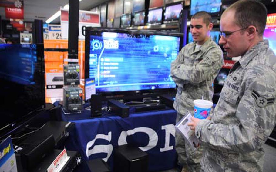 Airman 1st Class Kevin Cerven and Airman 1st Class Barry McCool, of the 374th Communications Squadron, check out new televisions at the Yokota Base Exchange on Tuesday. Servicemembers and their families say that with yen rates recently reaching 14-year highs, they are shopping for more holiday gifts online and on base. The Bank of Japan took measures to weaken the yen Tuesday, but currency traders reacted tepidly shortly afterward.