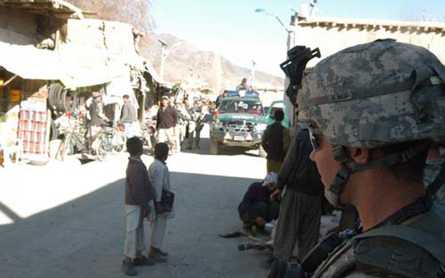 Sgt. Joshua Watkins of the 118th Military Police Company looks on as Afghan National Police officers distribute aid in the Jalrezy valley in Afghanistan&#39;s Wardak province. Watkins readily admits that the ANP need a lot of work, but that patience and effort to befriend the burgeoning force will pay dividends and help ensure loyalty. "Give them more time," he said. "Give us more time."