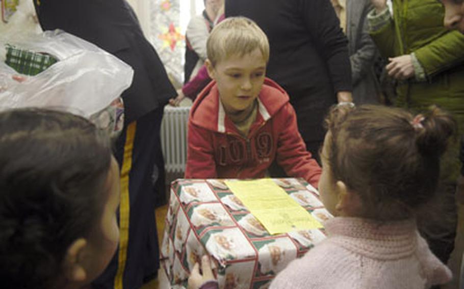 Lionel Weidanz, son of a U.S. European Command soldier, helps hand out gifts Tuesday at an orphanage in Stuttgart. For the past four years, EUCOM staff members have collected Christmas gifts for local needy children.