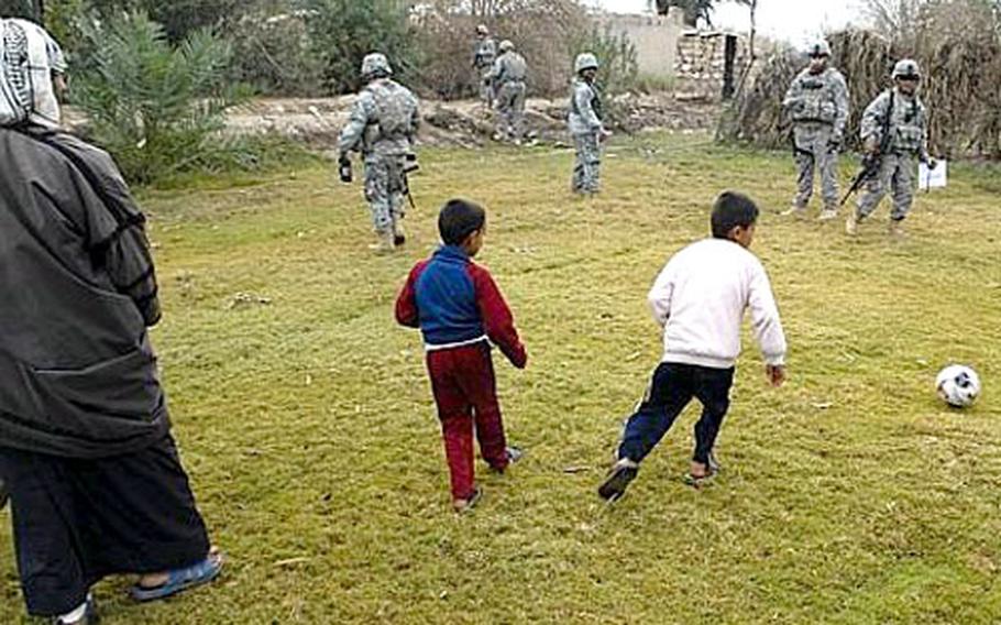 Children play with a soccer ball delivered by U.S. troops near Mahumudiyah, Iraq, during a Christmas morning patrol.