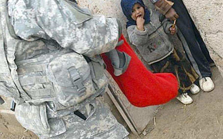 Staff Sgt. Reese Jacobs, Jr., offers candy to children at a farm near Mahmudiyah, Iraq, on Christmas Day.