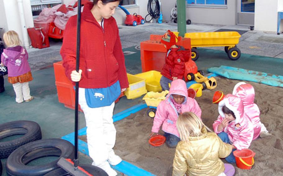 Erin Becote, a teacher in the preschool room at Yokosuka Naval Base&#39;s Child Development Center, talks with children as they play in the center&#39;s sandbox.