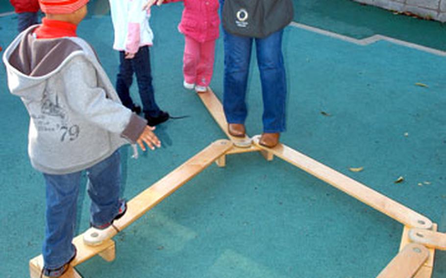 Rose San Agustin, the program leader for the preschool room at Yokosuka Naval Base&#39;s Child Development Center, demonstrates a plank-walking activity to children.